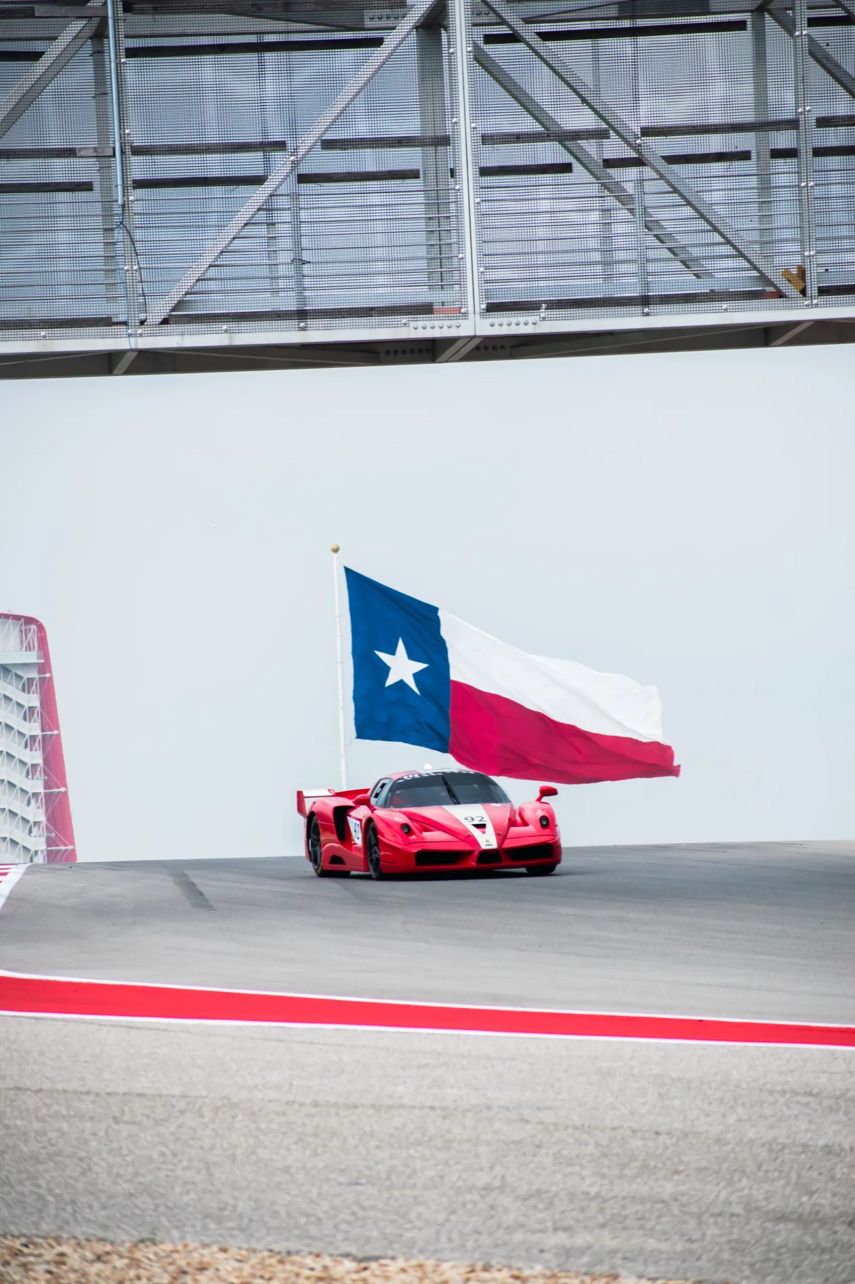Ferrari FXX in red, white and blue livery at Circuit of the Americas, Texas flag in the background