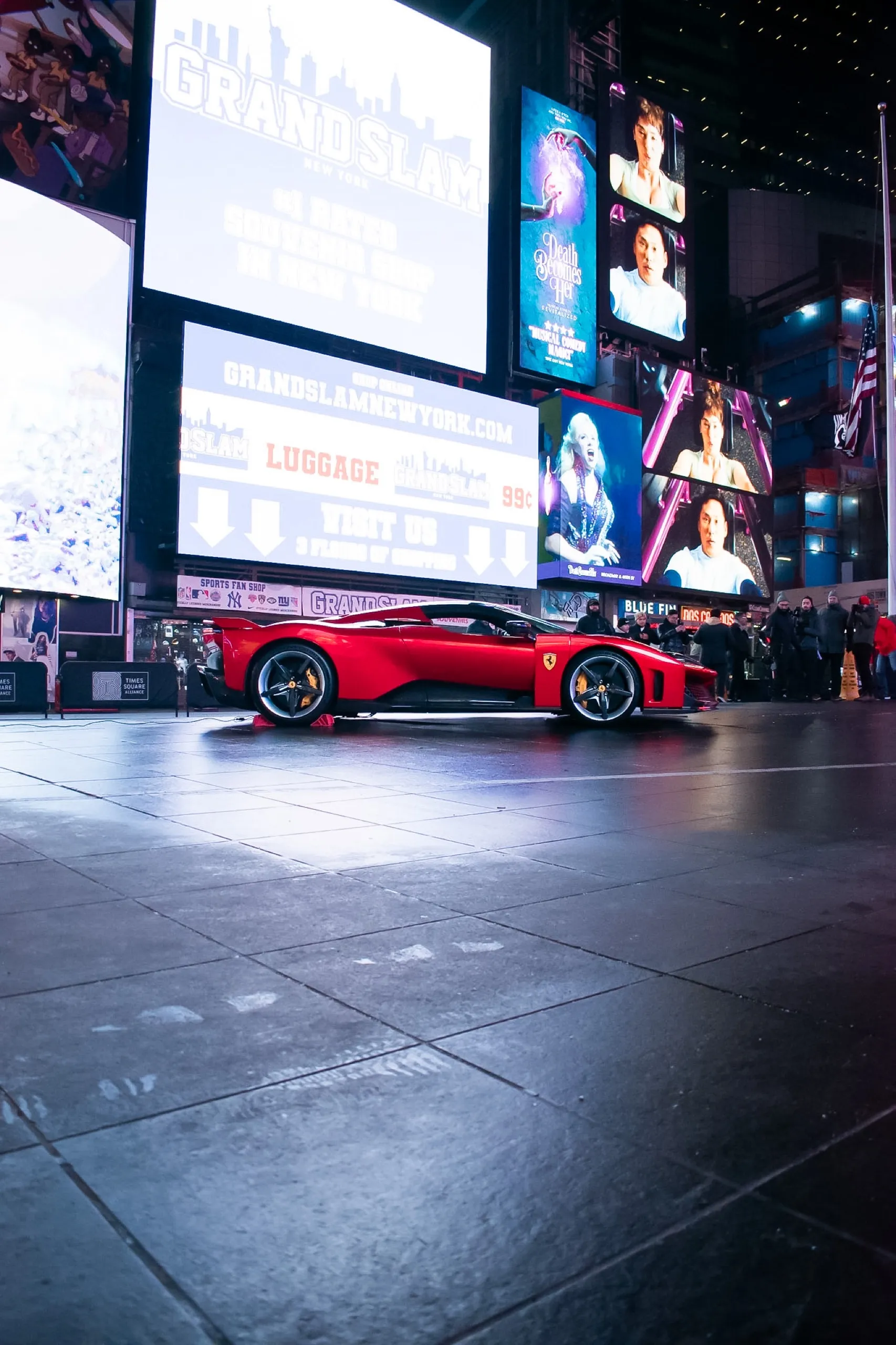 Red Ferrari Daytona SP3 displayed at night in Times Square, New York